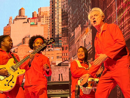 David Byrne performs with band members clad in orange jumpsuits.