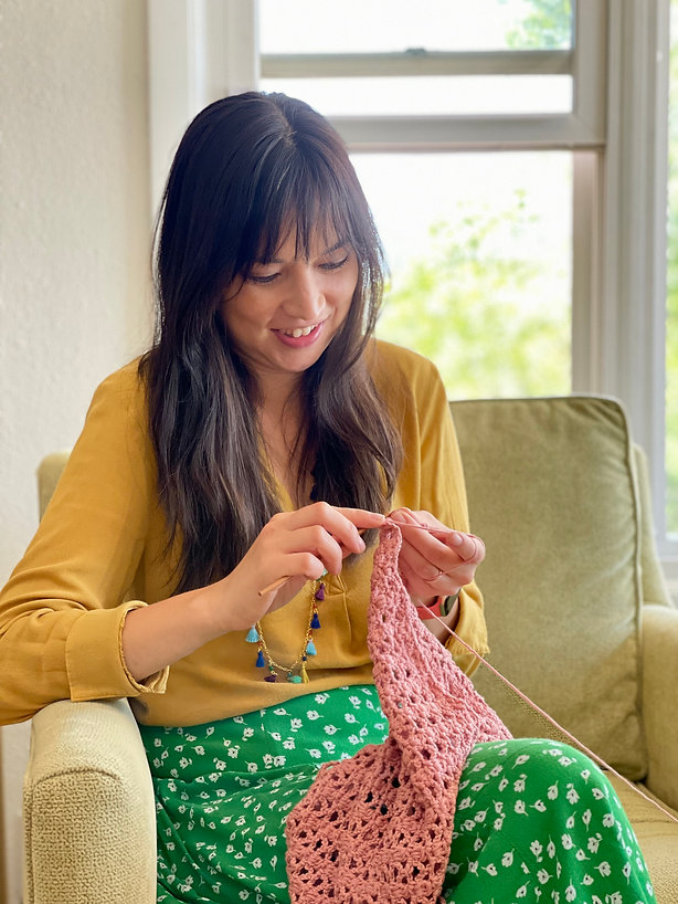 Image of Jenn Smith, owner and blogger for Smith Country crocheting infant of a window.