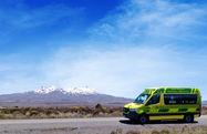 Ambulance parked in front of a mountain under a blue sky