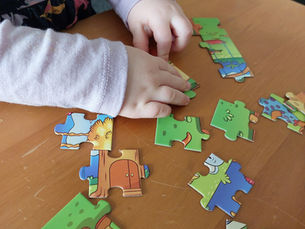 The hands of a child working on a colourful jigsaw puzzle