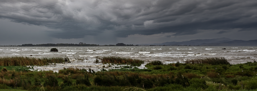 Storm clouds over rough water and reeds on a New Zealand shore (taken in 2018 and edited in Firefly), symbolising life’s storms and the hope found in Christian community.