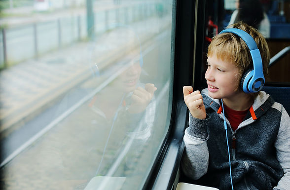 A young boy sits in a train with headphones on.