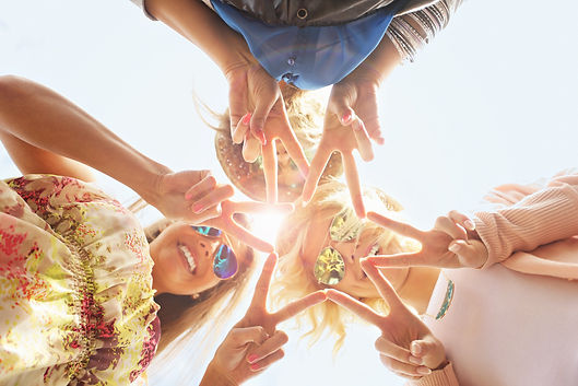 A group of three young adults look down into the camera creating a star with their fingers.