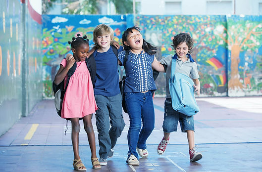 A group of four kids walk together laughing.