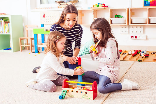 A women and two young girls play on the floor.