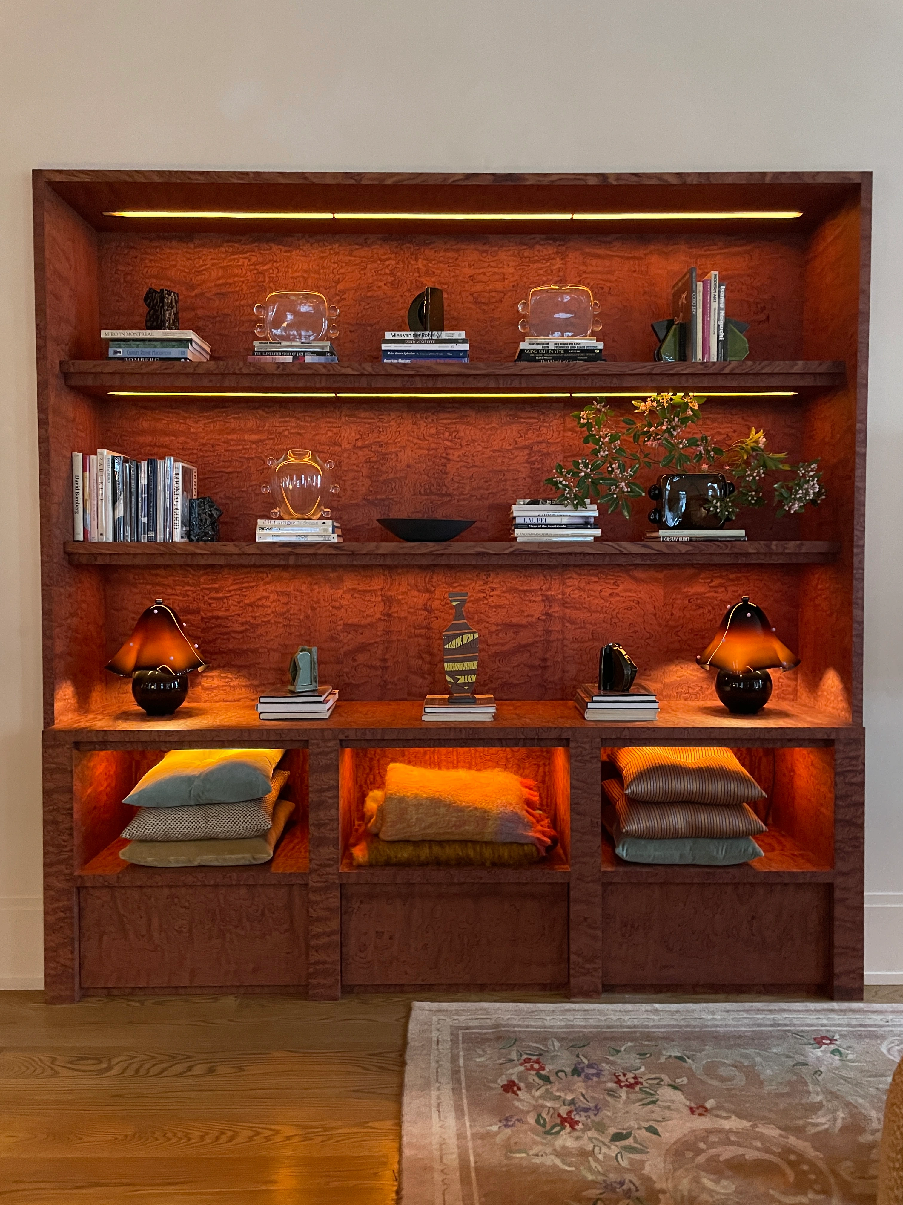 Customized beautifully grained wood shelving, and lighting in the nooks