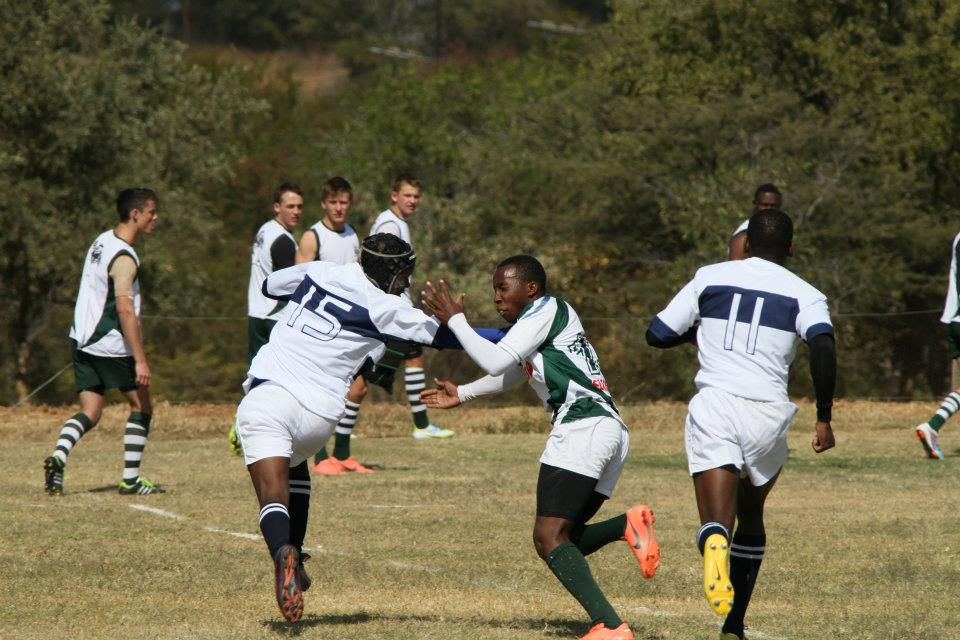 Tobias Matonhodze (number 15) executes the hand-off in a match against Harare's St John's College at Kyle College in 2015.