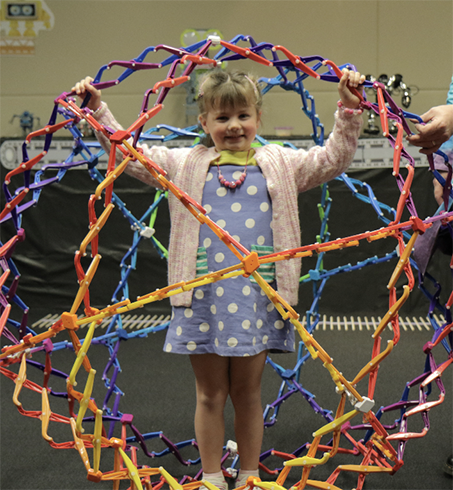 Child standing inside a large geodesic dome structure at science show.