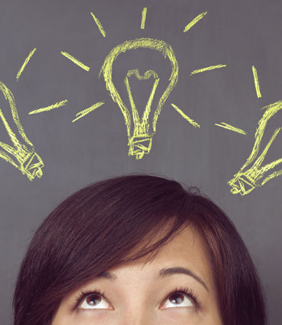 Woman looking up at light bulb drawings on a blackboard