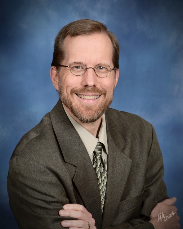 Smiling man in a suit and glasses with a blue background