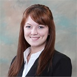 Smiling woman with long auburn hair in a black blazer.