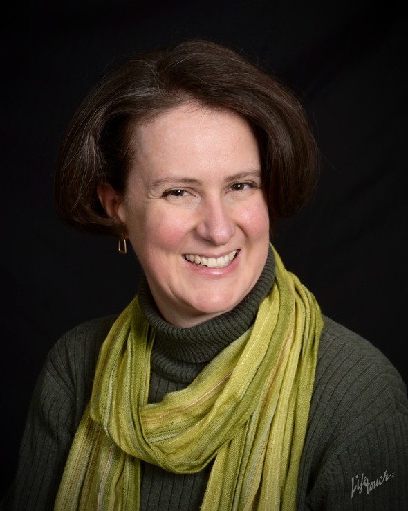 Smiling woman with brown hair, green turtleneck and scarf