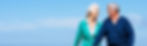 Smiling elderly couple walking together under a clear blue sky.