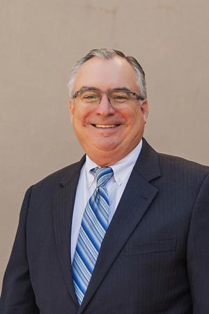 Smiling middle-aged man in a suit and blue striped tie.