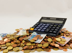 Calculatrice posée sur des pièces et billets en euros pour illustrer le remboursement de l'impôt sur le revenu.