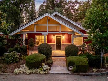 Front exterior of vacation rental home in Santa Rosa, CA with a path leading up to the front door. There are large windows and the home is surrounded by nature.