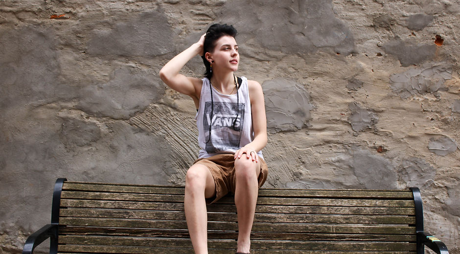 Photo of Tiarra Celeste sitting on a bench with a brick wall in the background.