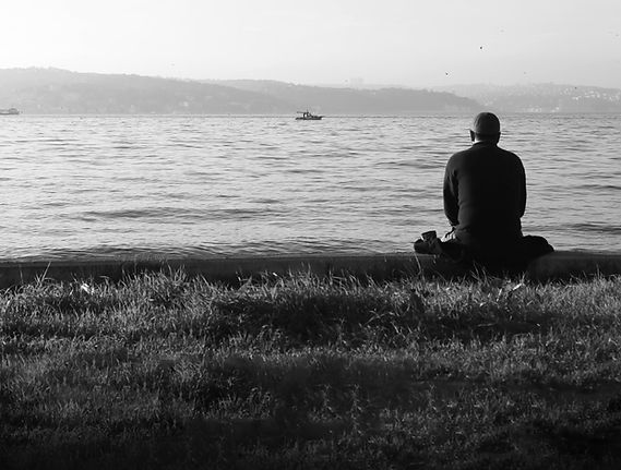 person-sits-looking-out-towards-still-water.jpg