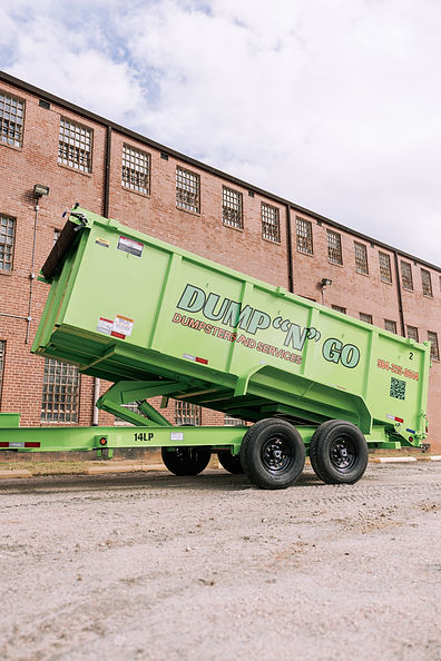 Green Dump ‘N’ Go dumpster trailer ready for hauling junk and debris near a brick building in Greensboro NC