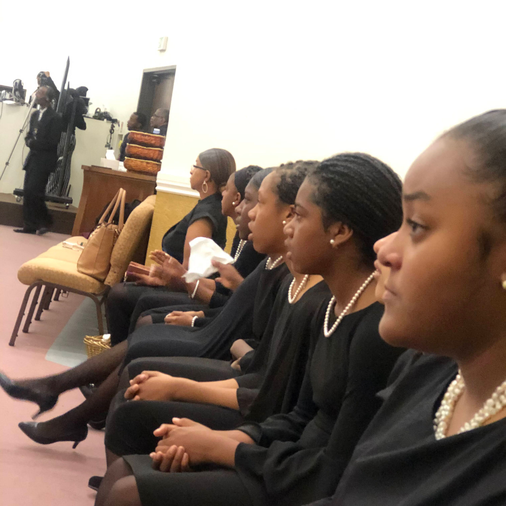 Young women in black dresses attend a ceremony