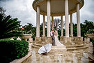 Bride and groom in a beautiful gazebo on a rainy day, with an open umbrella in front of the stairs. Fine aret wedding photography in the lower mainland.