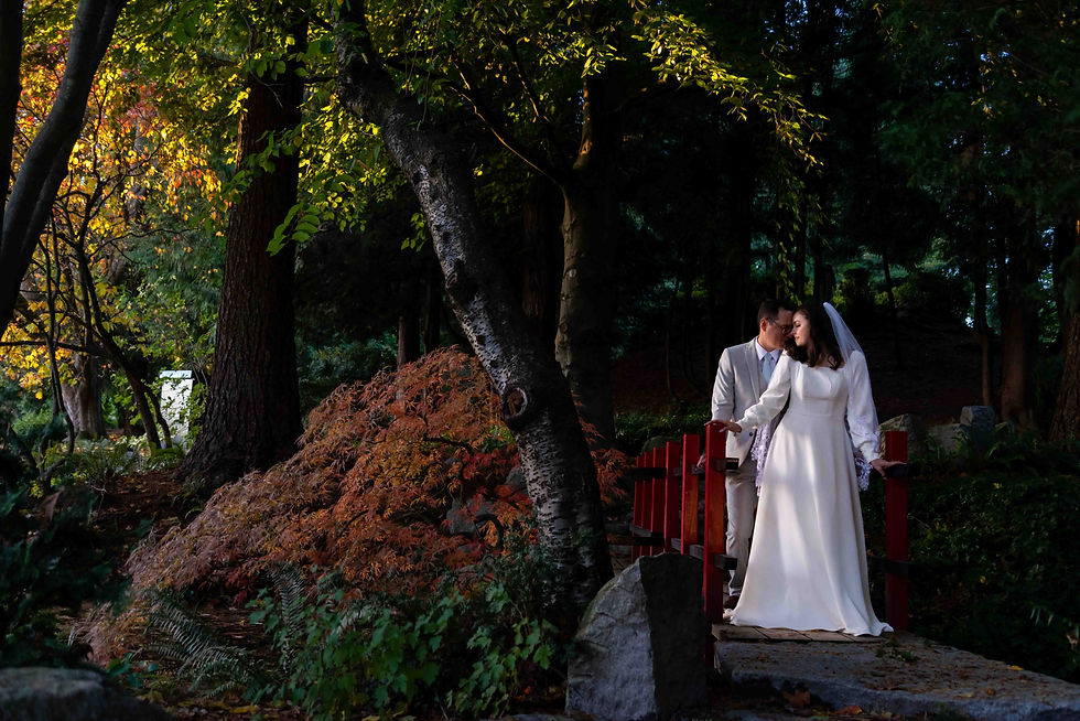 Tipperary Park wedding photo in New Westminster. Couple on a red bridge in romantic pose as the bride is lit by the evening sun.