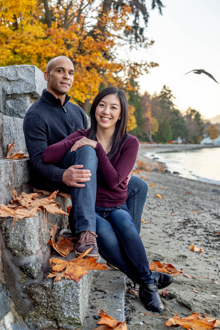 Interracial couple sitting on the seawall looking at the camera in Stanley park.