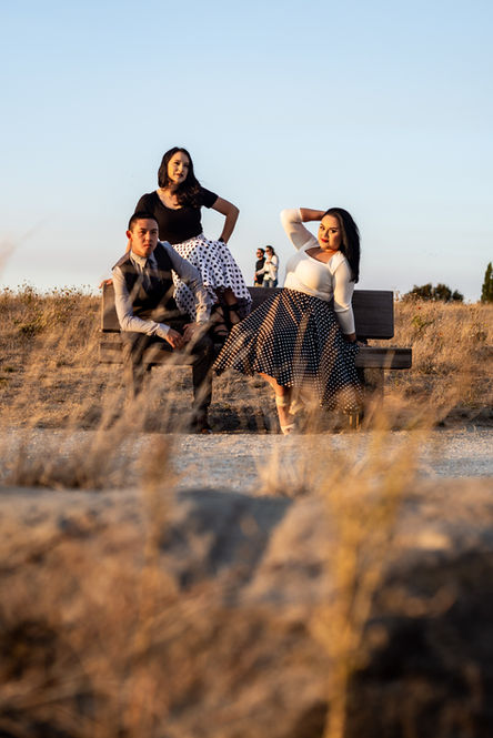 Family sitting on a bench through the long grass.