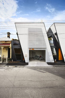 Outside view of a white modern industrial building with an open garage and motorbike inside.