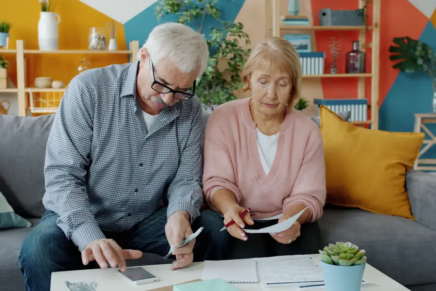 An older couple at home reading financial paperwork together before applying