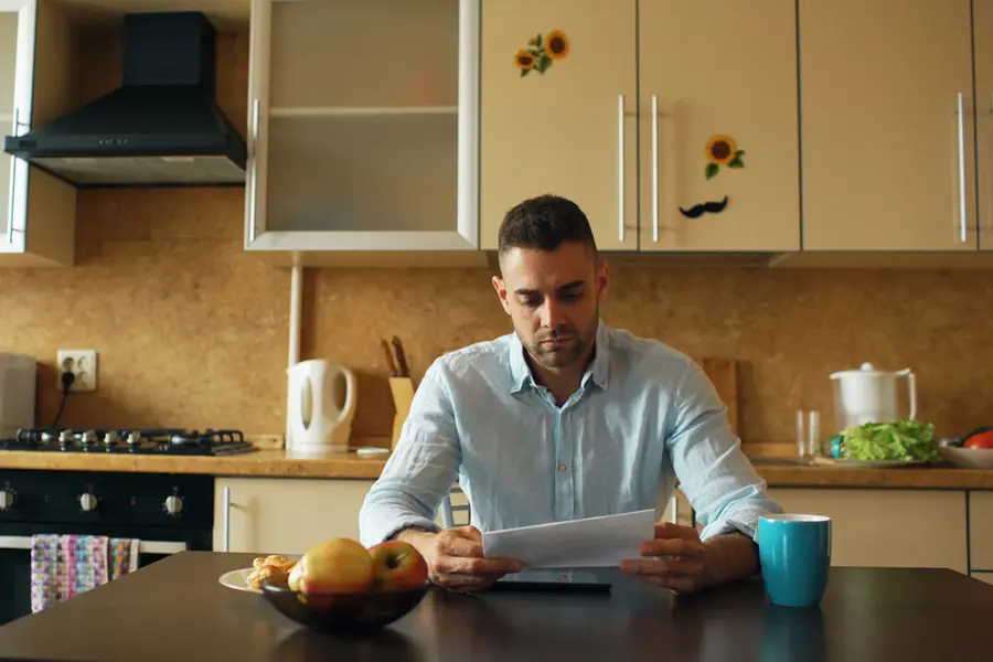 Homeowner reading a bill at the kitchen table after a missed direct debit before a mortgage application