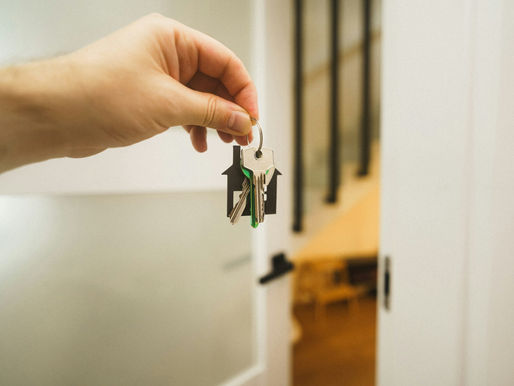 A hand holding a key in an open doorway, representing buying or remortgaging a home with bad credit.