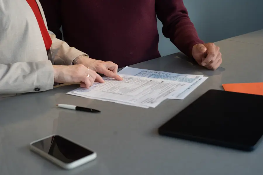 Two people reading paperwork at a table while checking mortgage options