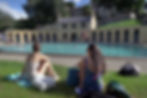 Two friends sitting on the lawn poolside at Cleveland Pools