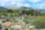 Hiker walking on path with hillside in the background