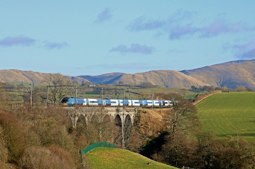 Train going over viaduct with mountain in distance