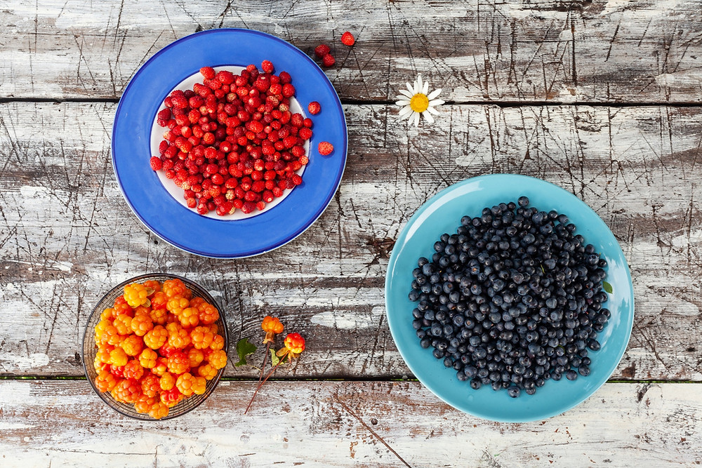 red, orange and black berries on plates on a table