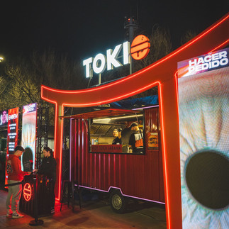 Food truck rojo TOKI bajo arco iluminado en la noche.