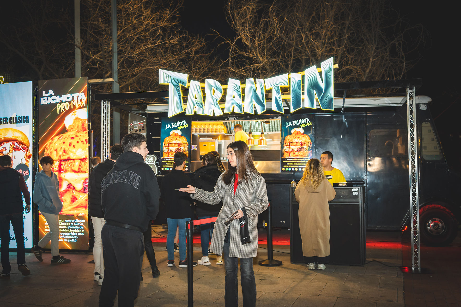 Clientes en fila frente al food truck 'TARANTIN' en un evento nocturno.