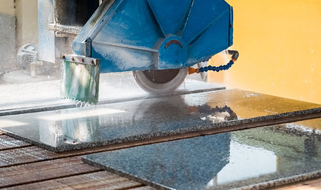 Close-up of a large bridge saw cutting a granite slab, preparing it to be made into a granite worktop