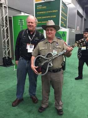 Tim White with a Texas law enforcement officer holding the aluminum-body Ridgewing guitar