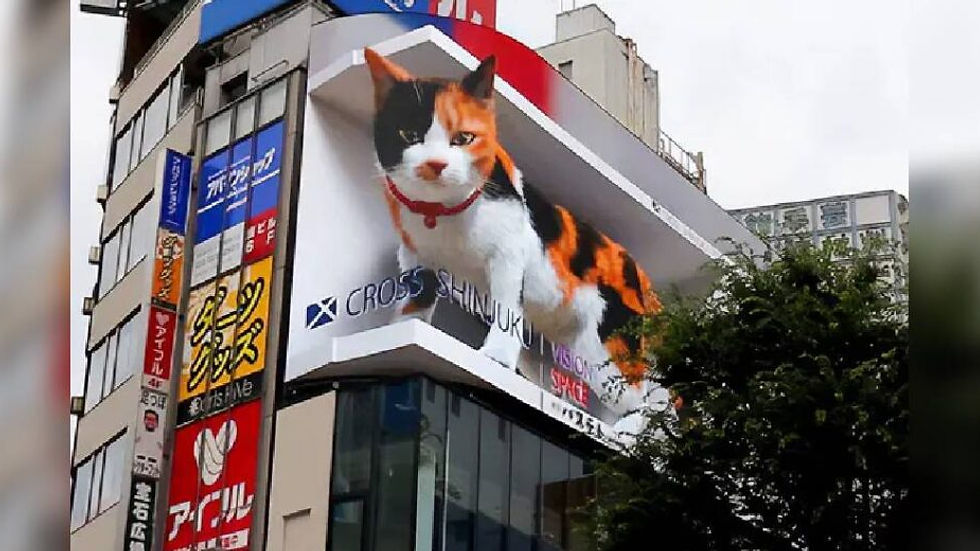 A large digital billboard in a city shows a 3D calico cat with a red collar. The sign reads "Cross Shinjuku Vision Space." Urban setting.