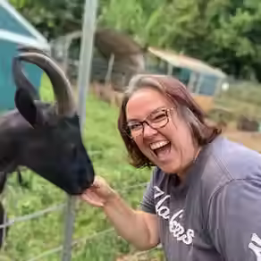 Kristie, our Executive Director, smiling with a very cute goat named Pili