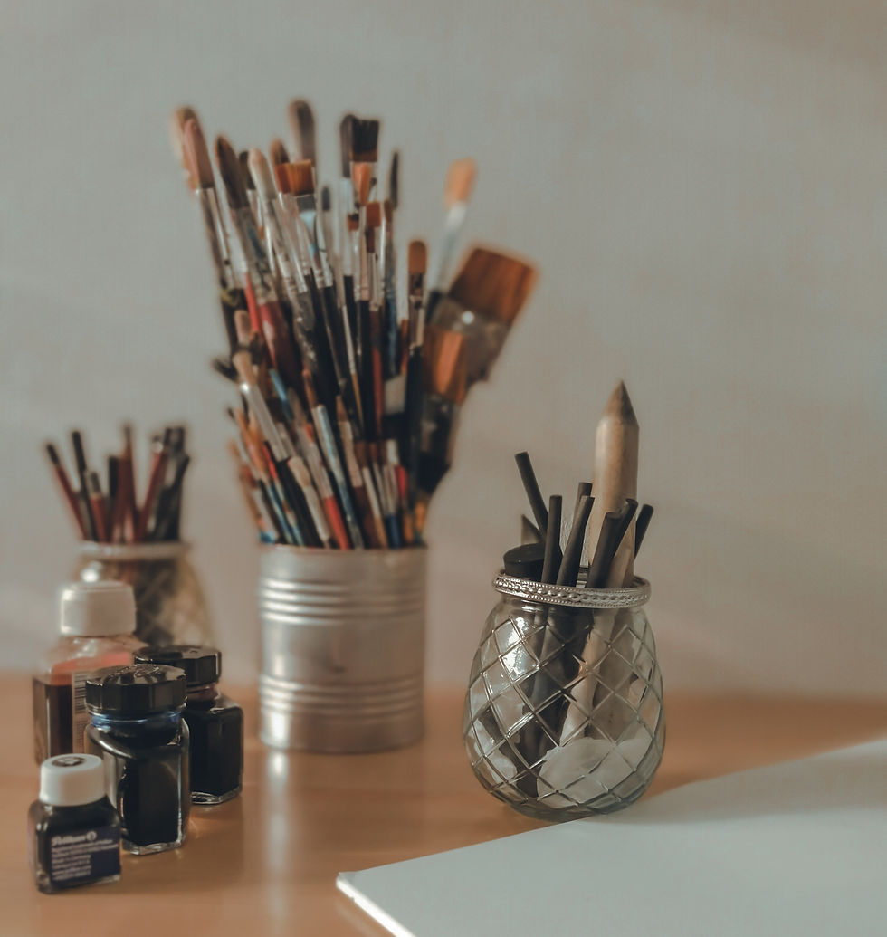 Materiais de desenho distribuídos em potes de vidro e metal e folhas de papel branco sobre uma mesa - foto