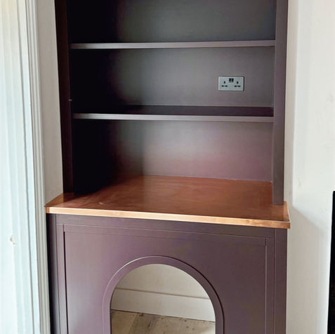 Custom alcove bookcase in deep-stained timber with curved dog bed arch and copper plate desktop
