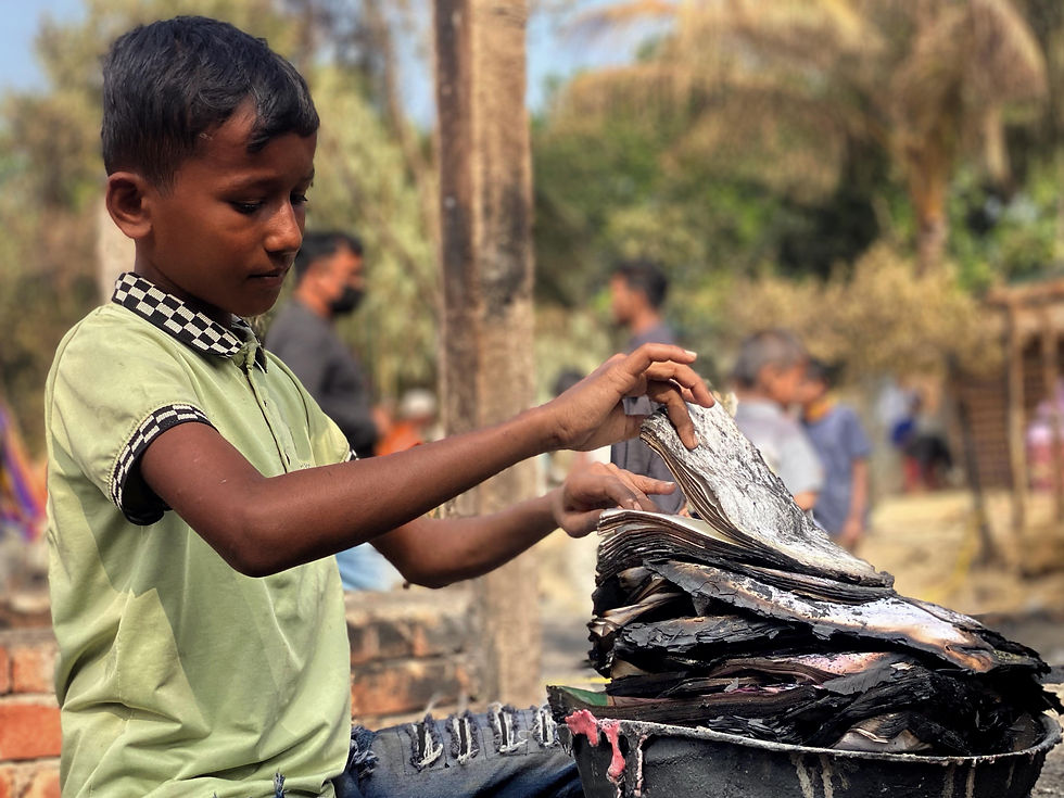 A boy goes through his burned school books. 2025 © Ayub Khan Dkl
