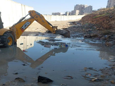 A construction vehicle surrounded by open sewage