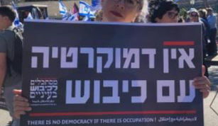 A woman holding a sign at a protest that reads "there is no democracy if there is occupation"