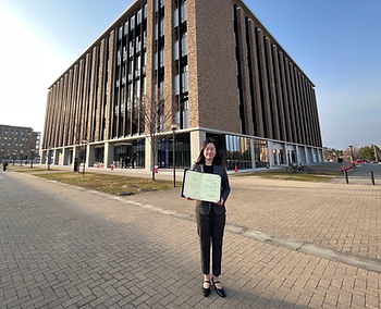 woman standing with diploma in front of building