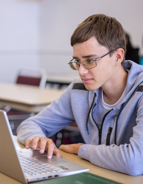 High school student working independently on a laptop in a classroom